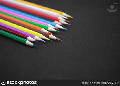 Selective focus on colorful pencils, crayon on black matte background with copy space. Back to school concept, Drawing concept. Top view, Closeup.