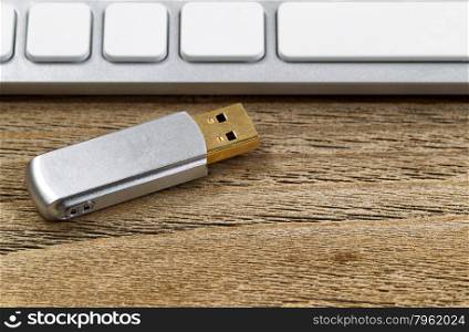 Selective focus on data thumb drive with partial keyboard in background. Layout in horizontal format on rustic wood.