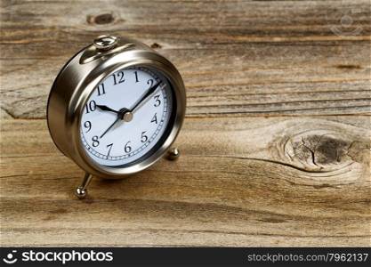 Selective focus on desktop metal clock in horizontal format on rustic wood.