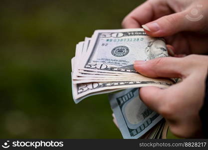 Selective focus on detail of USD banknotes. Counting or giving United States Dollars banknotes. World money concept, inflation and economy concept