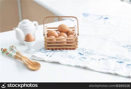 Selective focus on fresh egg placed on egg stand and raw chicken eggs in basket in home kitchen, wooden spoon and fork placed on table mat. Eggs for ingredient in breakfast concept