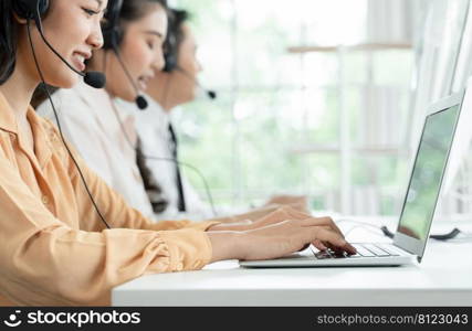 Selective focus on hand of young operator woman typing and working with headset smiling and doing customer support at work. Group of Asian employee work in telemarketing customer service teams