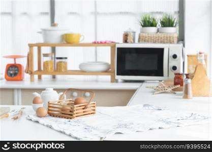 Selective focus on raw chicken eggs in basket and egg placed on egg stand in modern home kitchen with hot water pot, wooden spoon and fork placed on table mat. Eggs for ingredient in breakfast concept