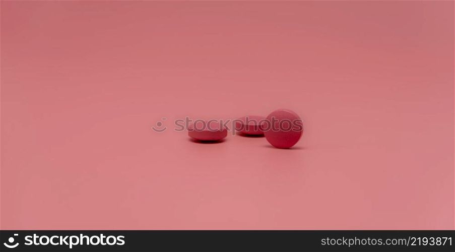 Selective focus on round pink tablet pill on pink background. Pharmacy horizontal web banner. Pharmaceutical industry. Prescription drug. World Health Day background. Vitamins and minerals concept.