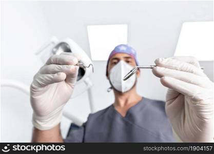 Selective focus on the tools that are using a male dentist with uniform and mask in a dental clinic. Selective focus on the tools that are using a dentist in a dental clinic