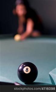 Selective focus shot of an eight ball over the pocket on a pool table