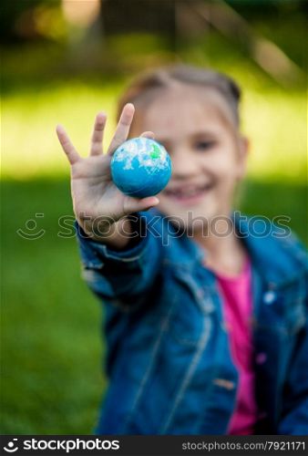 Selective focus shot of girl holding Earth in hand