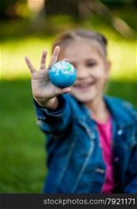 Selective focus shot of girl holding Earth in hand