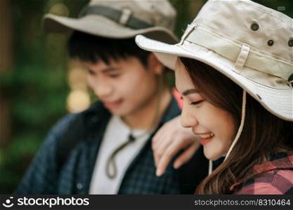 Selective focus, smiley pretty girl wearing trekking hat and her boyfriend looking on map while walking on forest trail, backpack travel concept 