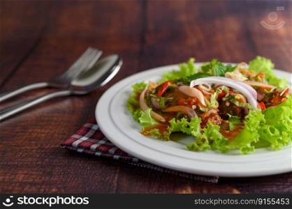 Selective focus Spicy salad of sardine with tomato sauce in white dish and sparken stainless spoon and fork over napkin on wooden table, copy space