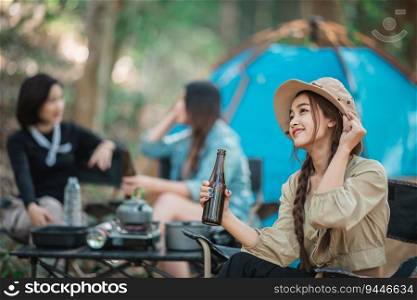 Selective focus, Young Asian pretty woman and her girl friends travelers relaxing in c&chairs at tent, They are cheering and drinking beer during c&ing, talking with fun and happy together