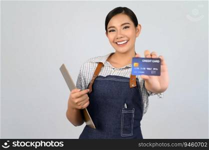 Selective focus, young asian woman in waitress uniform pose with credit card in hand, copy space to insert products for advertisement isolated on white background