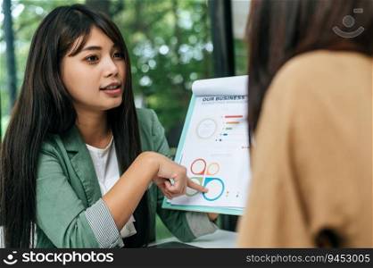 Selective focus, Young beautiful woman holding and pointing on report or paper work and talking while working with her friend at coffee shop