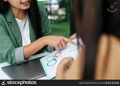 Selective focus, Young beautiful woman holding and pointing on report or paper work and talking while working with her friend at coffee shop