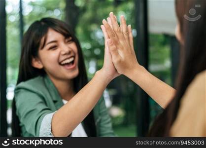 Selective focus, Young woman and her female colleague smile and doing high five with glad in successful in coffee shop