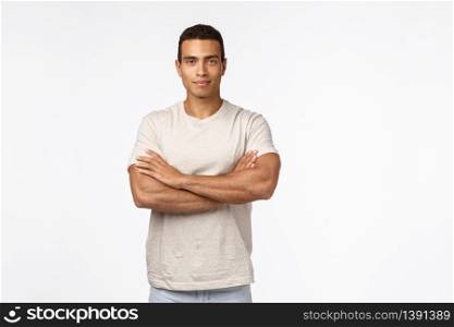 Self-assured and motivated good-looking male athlete in casual t-shirt, cross arms over chest in confident, assertive pose, smirk satisfied and proud, looking strong and powerful, white background.. Self-assured and motivated good-looking male athlete in casual t-shirt, cross arms over chest in confident, assertive pose, smirk satisfied and proud, looking strong and powerful, white background