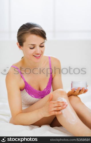 Self caring woman applying creme on leg