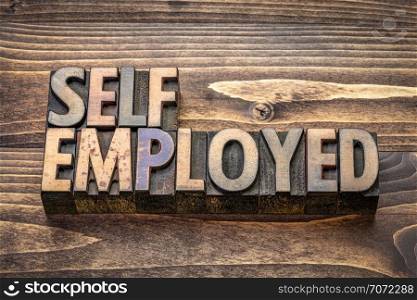 self employed word abstract in vintage letterpress wood type against grained wooden background