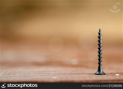 Self-tapping screw on wood on the table. On a wooden background. High quality photo. Self-tapping screw on wood on the table.