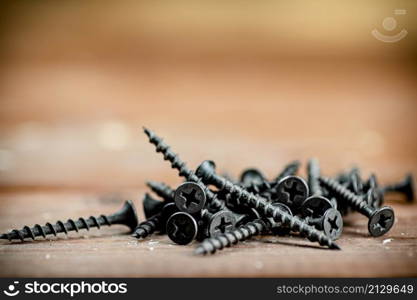 Self-tapping screws on the table. On a wooden background. High quality photo. Self-tapping screws on the table.