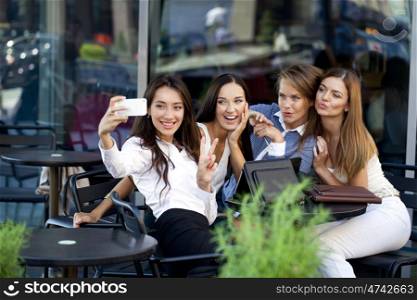 Selfie Four women sitting in a cafe on the street