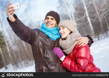 Selfie in park. Happy young couple in winter park having fun