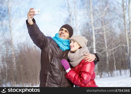 Selfie in park. Happy young couple in winter park having fun