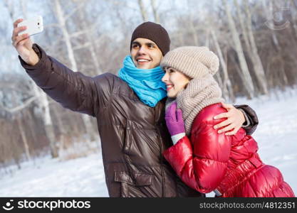 Selfie in park. Happy young couple in winter park having fun