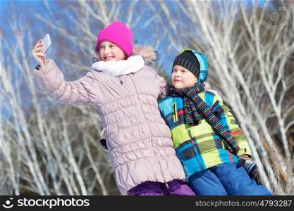 Selfie in park. Two happy kids making selfie photo in winter park