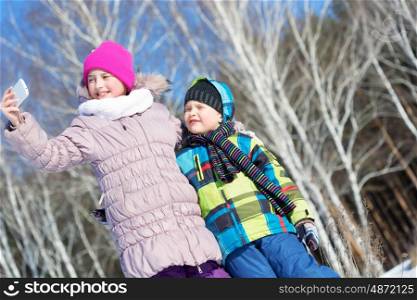 Selfie in park. Two happy kids making selfie photo in winter park
