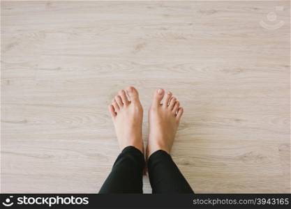 Selfie of bare feet on wooden floor background, top view