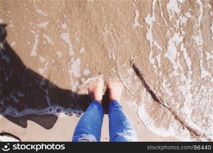 Selfie of bare feet, woman standing on the beach