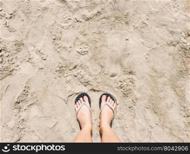 Selfie of feet in sandals shoes on beach sand background, top view&#xD;
