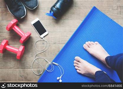 Selfie of feet yoga woman, smartphone, sport equipments and sport shoes on wood floor