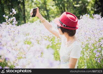 Selfie time. Joyful young women making selfie by her smart phone in a violet meadow.