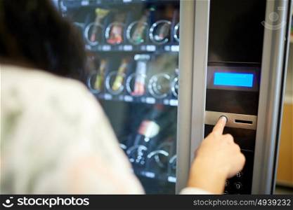 sell, technology and consumption concept - woman pushing button on vending machine operation panel. woman pushing button on vending machine