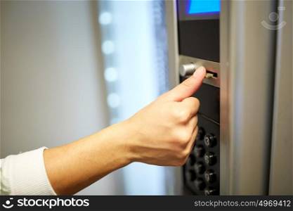 sell, technology, people, finances and consumption concept - hand inserting euro coin to vending machine. hand inserting euro coin to vending machine