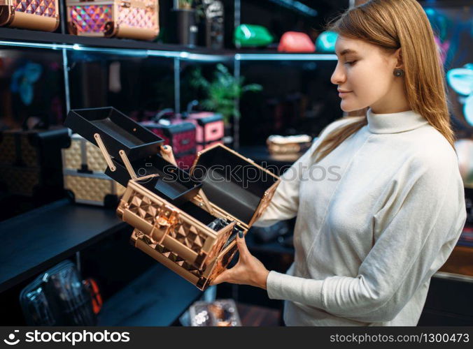 Seller consultant helps the woman with the choice of case for cosmetics in the make-up shop. Female customer in beauty store. Consultant helps woman with choice in make-up shop