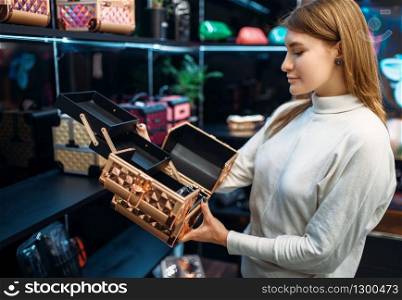 Seller consultant helps the woman with the choice of case for cosmetics in the make-up shop. Female customer in beauty store. Consultant helps woman with choice in make-up shop