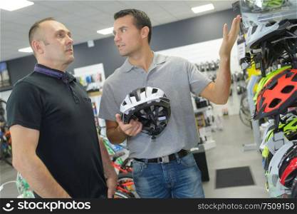 seller helps customer to choose helmet for cycling in shop