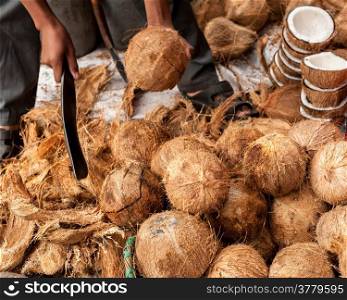 Seller opens tropical coconuts at traditional food marketplace
