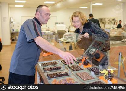 seller with dark and white chocolates confectionery at display