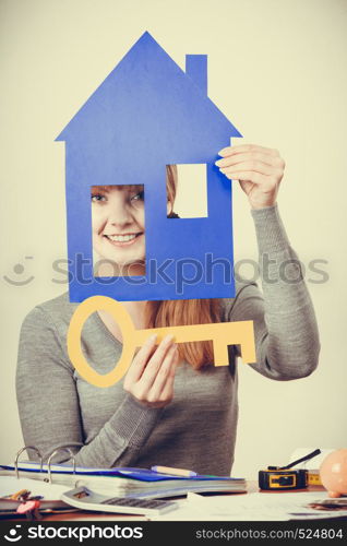 Selling and buying real estate concept. Young blonde smiling positive female estate agent ready to sell house home.. Enjoyable estate agent with house ang key.