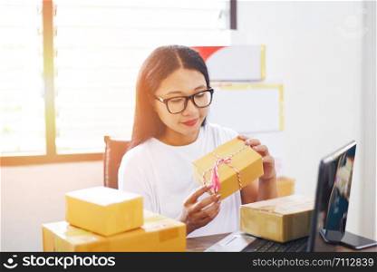 selling online ecommerce shipping online shopping delivery and order startup small business owner working / asian young woman packing cardboard box parcel delivery to customer cash on delivery