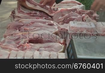 Selling pork meat at street market, vendor serving customer