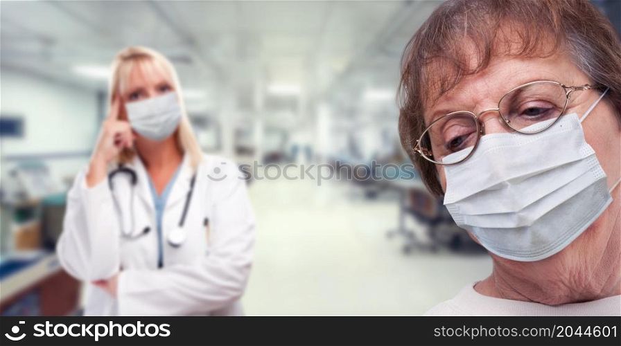 Senior Adult Female Looking Down as Doctor Stands Behind All Wearing Medical Face Masks Within Hospital.