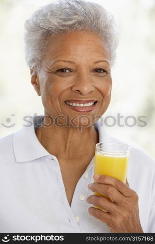 Senior Adult Holding A Glass Of Fresh Orange Juice, Smiling At The Camera