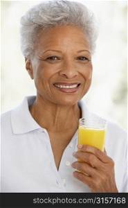 Senior Adult Holding A Glass Of Fresh Orange Juice, Smiling At The Camera