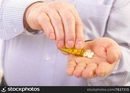 Senior adult man holds medicine capsule in his hand. Senior man taking pill