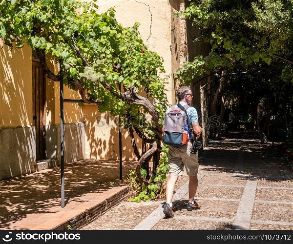 Senior adult photographer strolls through the Huerto de Calixto y Melibea gardens near the cathedrals in Salamanca Spain. Photographer walks through the gardens in Salamanca Spain